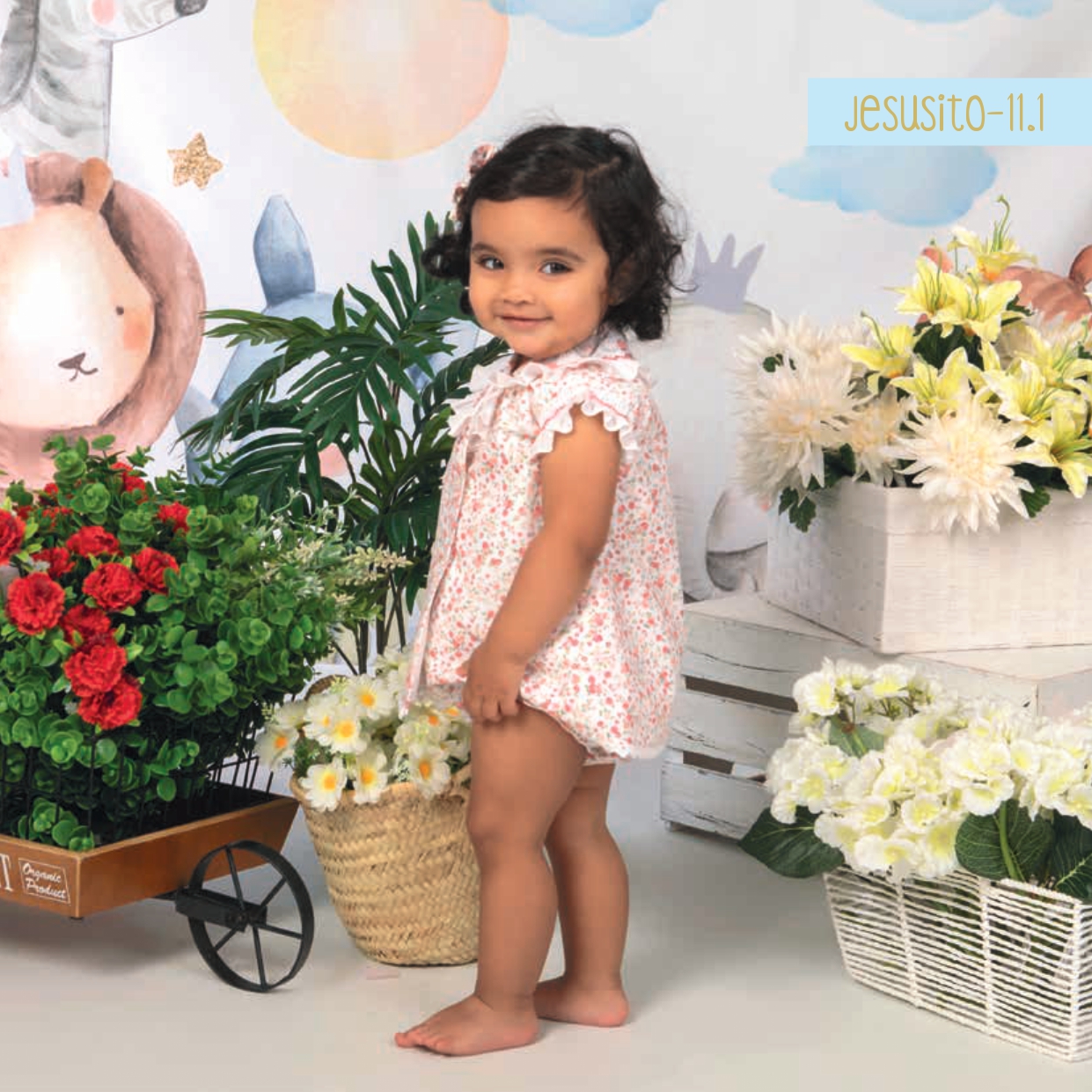 Vestido de bebé artesanal con nido de abeja bordado a mano y estampado floral coral sobre fondo crema